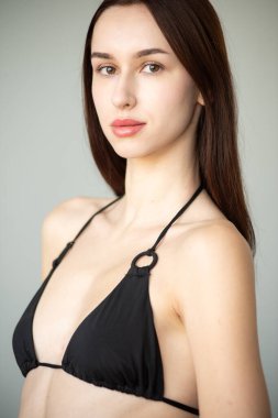 Stüdyoda poz veren siyah mayo giyen genç kız.