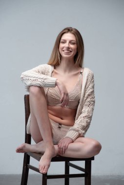 Ahşap sandalyede iç çamaşırlarıyla oturan genç kadın. Stüdyo resmi