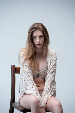 Stüdyoda tahta taburede oturan güzel bir kadın.