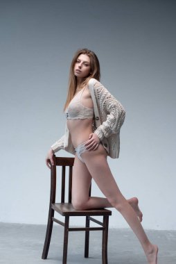 Genç, güzel bir kız, beyaz dantelli bir elbise ve siyah bir ceket giyiyor.