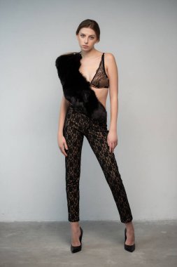 Gri arka planda siyah leopar kürklü genç bir kız.