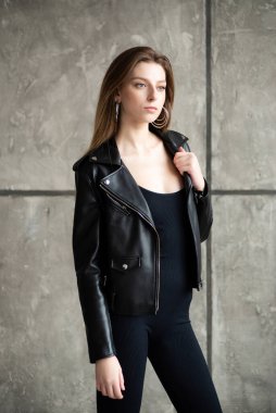 Deri ceket ve siyah pantolon giyen genç kadın..
