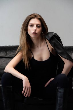 Beyaz arka planda siyah deri ceketli seksi bir kızın portresi.
