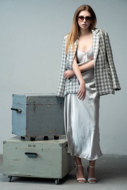 Gri arka planda bavulu olan genç bir kadın. seyahat ve tatil