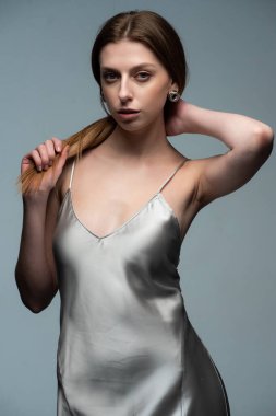 Uzun saçlı, parlak makyajlı genç bir kız stüdyoda poz veriyor.