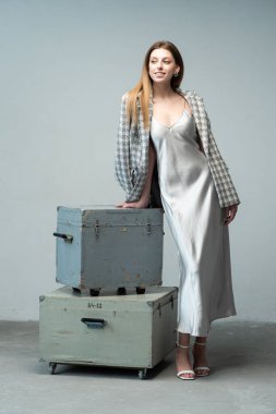 Gri bavullu şık gri elbiseli genç kadın.