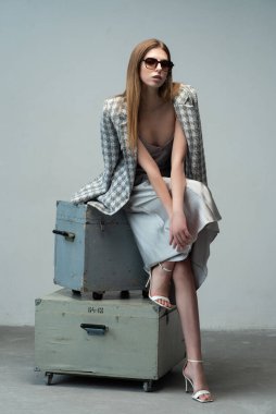 Stüdyoda poz veren bir model. Moda kıyafetleri ve güneş gözlüklü genç kadın..