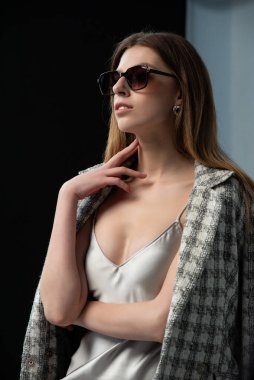 Siyah arka planda şık giyinmiş genç bir kadın.