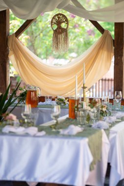 Restoranda bir ziyafet için düğün süsleri bahçede servis edilir, çiçeklerle süslenir ve mumlarla süslenir. Masa düğün için dekore edildi.