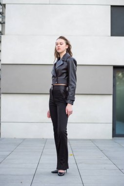 Şık giyinmiş, binanın yanında poz veren güzel bir kız.