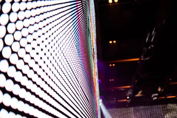 Elektronik müzik konserinde veya gece partisi etkinliğinde parlayan piksellerin ve dinamik sahne ışıklandırmasının soyut arka planında dijital ekranda renkli LED ışıkları