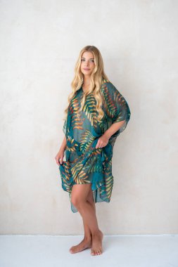 Eski bir duvarın arkasında elbise giymiş güzel sarışın bir kadın.