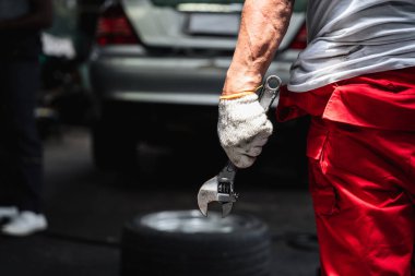 Garajda İngiliz anahtarı tutan tamirci eliyle yakın çekim..