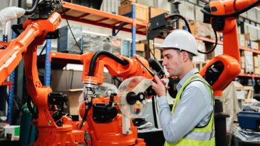 Industrial engineers control the automatic arms machine welding robotics in industrial manufacturing factories.