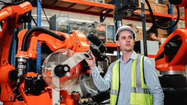 Industrial engineers control the automatic arms machine welding robotics in industrial manufacturing factories.