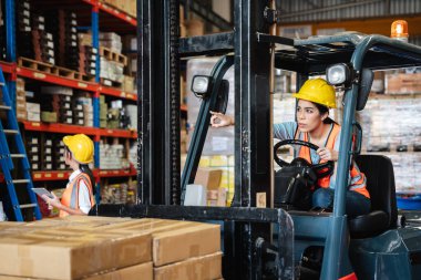 Portrait of a woman working with a forklift in a warehouse.