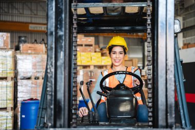 Portrait of a woman working with a forklift in a warehouse with her looking at the camera.