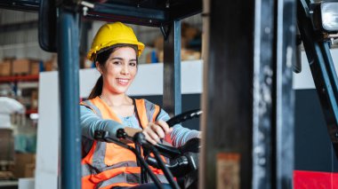 Portrait of a woman working with a forklift in a warehouse with her looking at the camera.