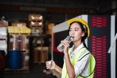 Warehouse workers relax and drink water from bottles in warehouse.