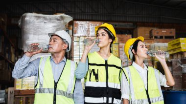 Warehouse workers relax and drink water from bottles in warehouse.
