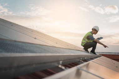Servis mühendisi hasar görmüş bir parça var mı diye çatıdaki güneş hücresini kontrol ediyor. Mühendis işçisi güneş paneli kuruyor. Temiz enerji kavramı.