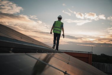 Servis mühendisi hasar görmüş bir parça var mı diye çatıdaki güneş hücresini kontrol ediyor. Mühendis işçisi güneş paneli kuruyor. Temiz enerji kavramı.