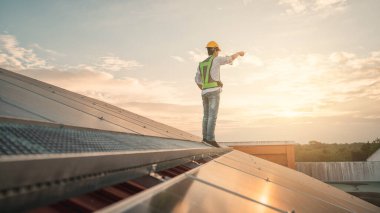 Servis mühendisi hasar görmüş bir parça var mı diye çatıdaki güneş hücresini kontrol ediyor. Mühendis işçisi güneş paneli kuruyor. Temiz enerji kavramı.