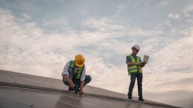 Servis mühendisi hasar görmüş bir parça var mı diye çatıdaki güneş hücresini kontrol ediyor. Mühendis işçisi güneş paneli kuruyor. Temiz enerji kavramı.