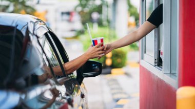 Young Man receiving coffee at drive thru counter., Drive thru and take away for protect covid19.	