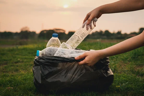Kapalı el, parkta çöp plastiği topluyor. Çimlerin üzerinde plastik şişe temizleyen bir gönüllü. Çevre, geri dönüşüm ve koruma kavramı.