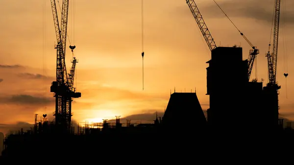 Silhouette of Construction site with crane and mechanical equipments. Building Site with Silhouetted Crane in the City.