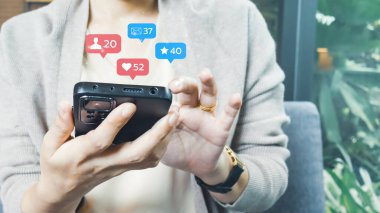 Genç kadın cep telefonunu sosyal medyayı kullanarak, insanlarla çevrimiçi bağlantı kurarak tutuyor. Teknoloji konsepti, iletişim, iş dünyası ve çevrimiçi pazarlama.