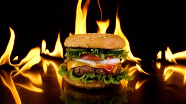 Ateşin arka planında nefis bir burger. Lezzetli burger, taze lahana, soğan, domates ve ızgara biftek. Fast food