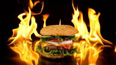 Ateşin arka planında nefis bir burger. Lezzetli burger, taze lahana, soğan, domates ve ızgara biftek. Fast food