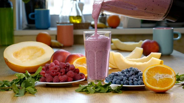 在新鲜水果和浆果的背景下 覆盆子蓝莓梅子冰沙被倒入杯子中 这种水果鸡尾酒准备好了 健康和素食概念 — 图库照片