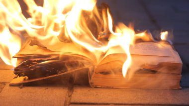 Açık bir kitap yanıyor. Büyük, parlak bir alev, karanlıkta eski bir yayınla ilgili yanan bir kağıt. Kitap Yakma - Sansür Konsepti