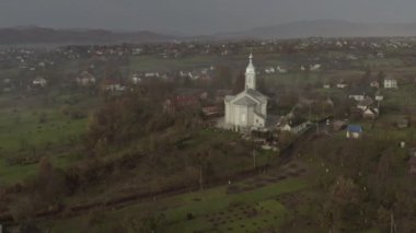 İnsansız hava aracı sonbaharda sabah köydeki kilisenin üzerinde uçar.