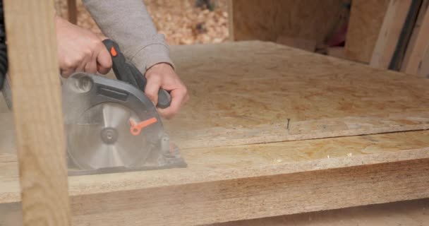 合板を切るために円形の鋸を使用して労働者のクローズアップ フレーム技術を利用した木造新住宅の建設 — ストック動画