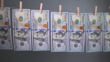 Yüz dolarlık banknotlar gri arka planda çamaşır iğnesi ipiyle kurudu. Dolar 'ın finansal konsepti. Para aklama kavramı.