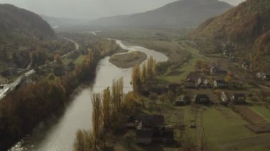 İnsansız hava aracı sonbaharda dağlarda, kırsal bölgede nehrin üzerinde uçar.