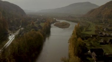 İnsansız hava aracı sonbaharda dağlarda, kırsal bölgede nehrin üzerinde uçar.