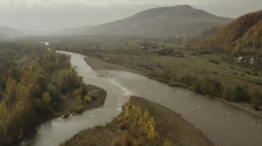 İnsansız hava aracı sonbaharda dağlarda, kırsal bölgede nehrin üzerinde uçar.