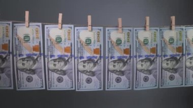 Yüz dolarlık banknotlar gri arka planda çamaşır iğnesi ipiyle kurudu. Dolar 'ın finansal konsepti. Para aklama kavramı.