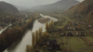 İnsansız hava aracı sonbaharda dağlarda, kırsal bölgede nehrin üzerinde uçar.