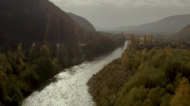 İnsansız hava aracı sonbaharda dağlarda, kırsal bölgede nehrin üzerinde uçar.