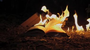 An open book is on fire. Big bright flame, burning paper on old publication in the dark. Book Burning - Censorship Concept, slow motion, close-up, 4K