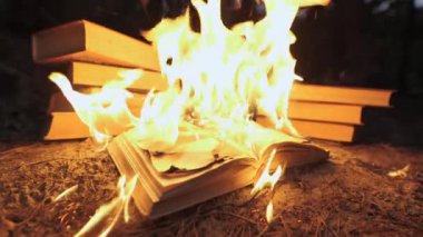 An open book is on fire. Big bright flame, burning paper on old publication in the dark. Book Burning - Censorship Concept, slow motion, close-up, 4K
