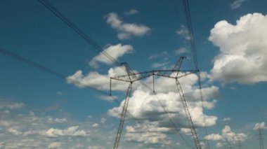 Yüksek voltaj pilonları üzerinde hareket eden bulutların zamanı. Dünya 'da elektrik krizi. Elektrik hatlarında yeşil enerji. Güç üretimi. 4K