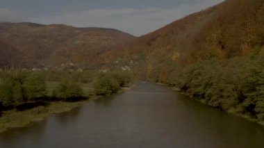 İnsansız hava aracı sonbaharda dağlarda, kırsal bölgede nehrin üzerinde uçar.