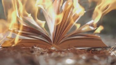 Açık bir kitap yanıyor. Büyük, parlak bir alev, karanlıkta yavaş çekimde eski yayınla ilgili yanan bir kağıt. Kitap Yakma - Sansür Konsepti